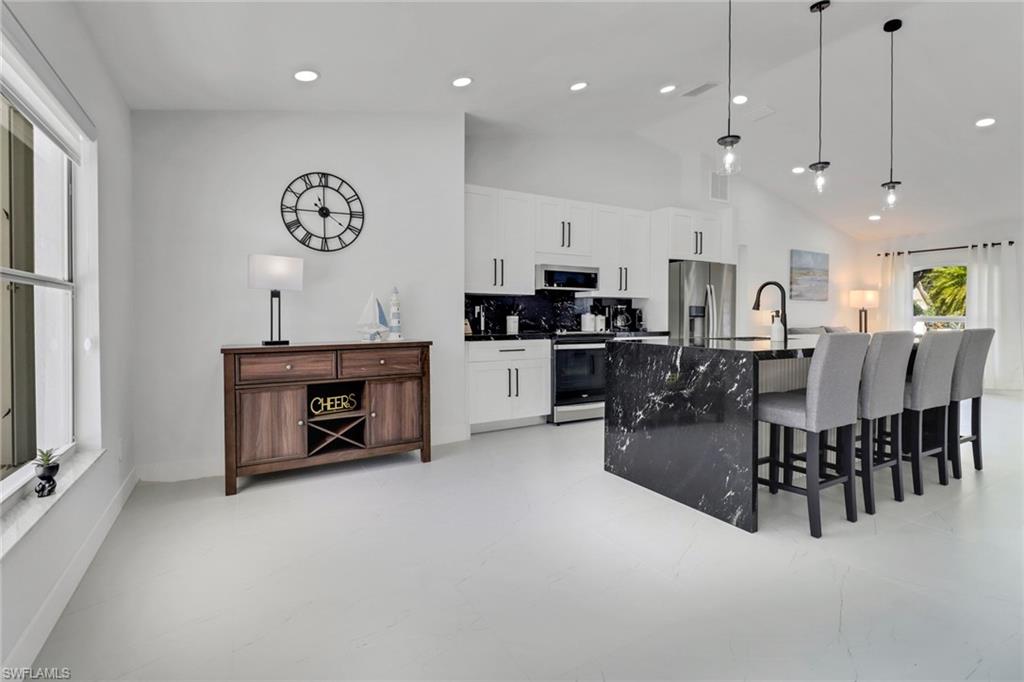 172 Plantation Circle Naples, FL 34104 - Photo 8 of 36 a kitchen with stainless steel appliances granite countertop a stove top oven a sink a dining table and chairs with wooden floor