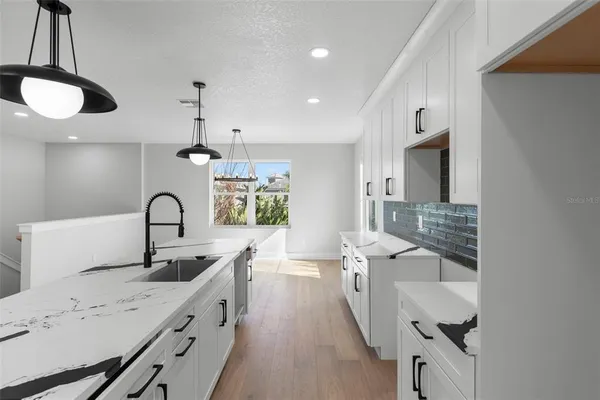 a large kitchen with a sink stainless steel appliances and cabinets