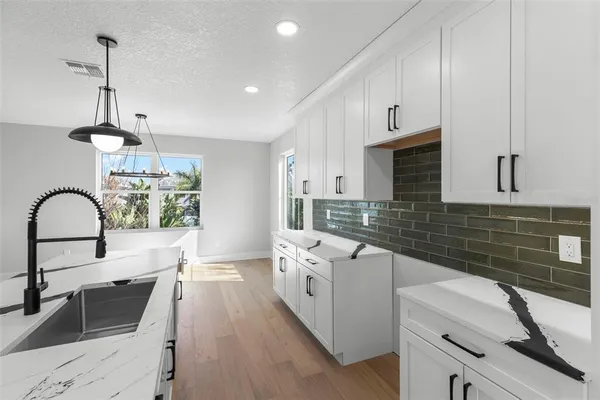 a open kitchen with stainless steel appliances granite countertop a stove and white cabinets