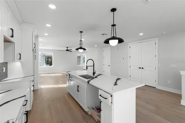 a kitchen with sink stove and white cabinets with wooden floor