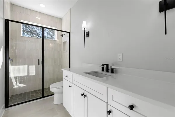 a bathroom with a granite countertop sink a toilet and shower