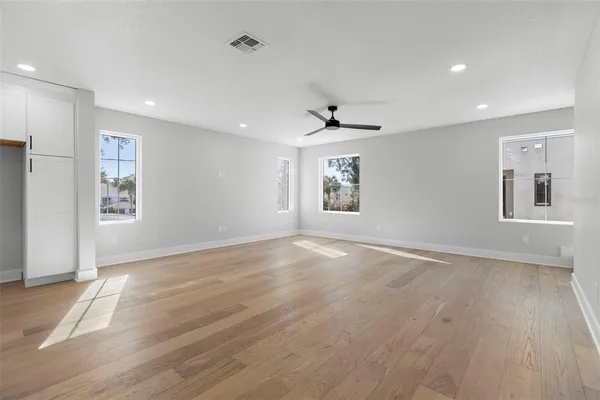 a view of an empty room with a window and wooden floor