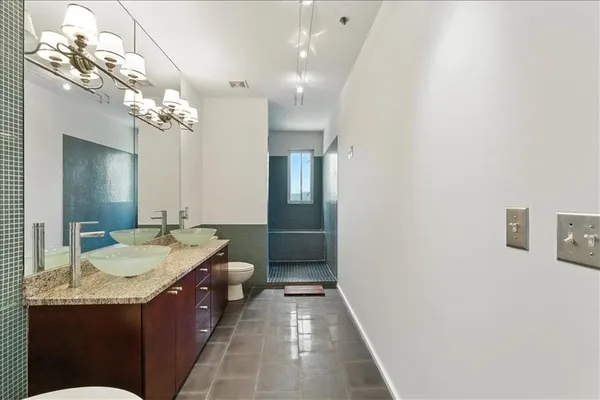 a bathroom with a granite countertop sink a toilet a mirror and shower