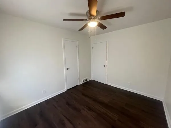 an empty room with wooden floor and fan