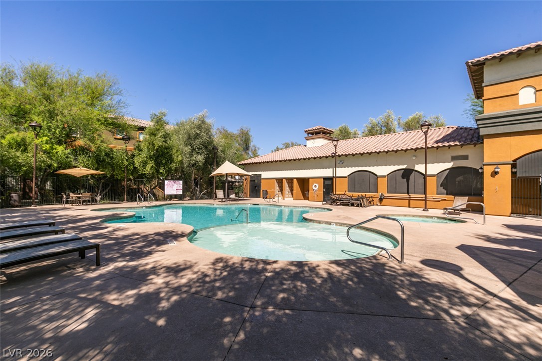 4650 Ranch House Road, Unit 46 North Las Vegas, NV 89031 - Photo 37 of 38 Sun-drenched patio spaces surround a sparkling community pool and spa beneath clear blue skies.