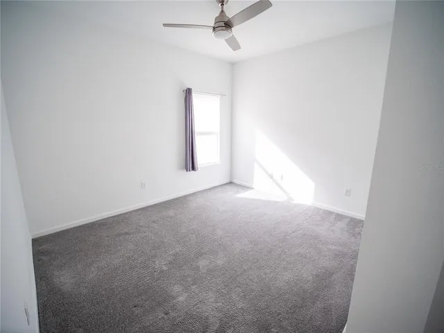 an empty room with a window and a ceiling fan