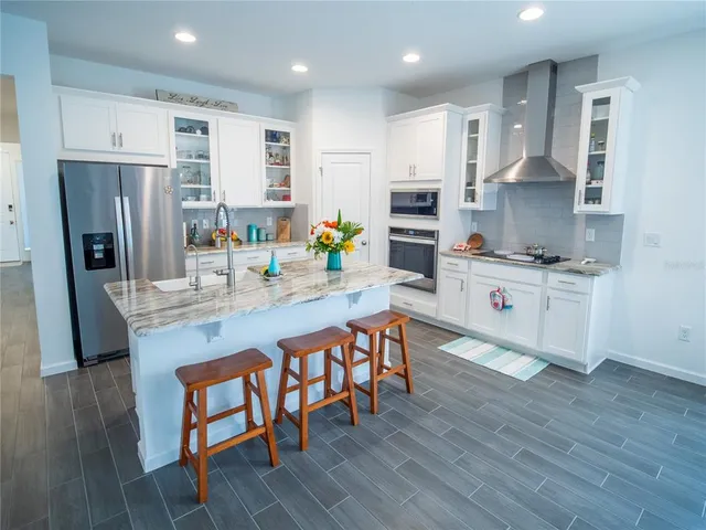 a kitchen with stainless steel appliances a sink a stove a refrigerator cabinets and wooden floor