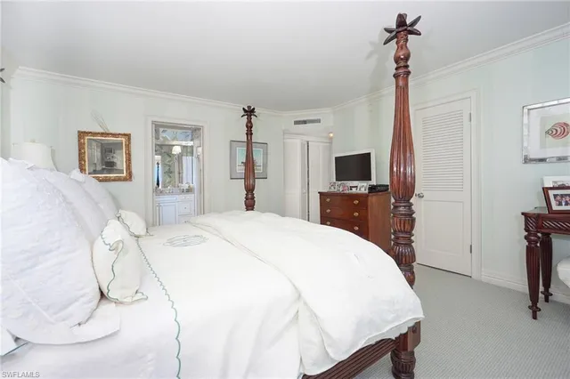 a spacious bedroom with a bed and a flat tv screen on the table