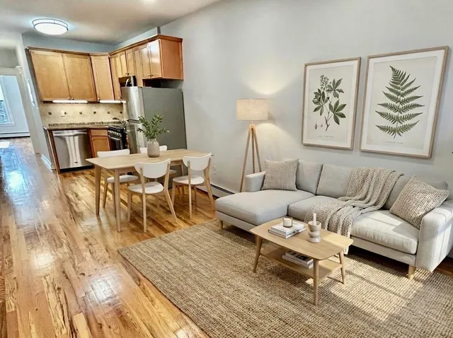 a living room with a couch and a dining table with wooden floor