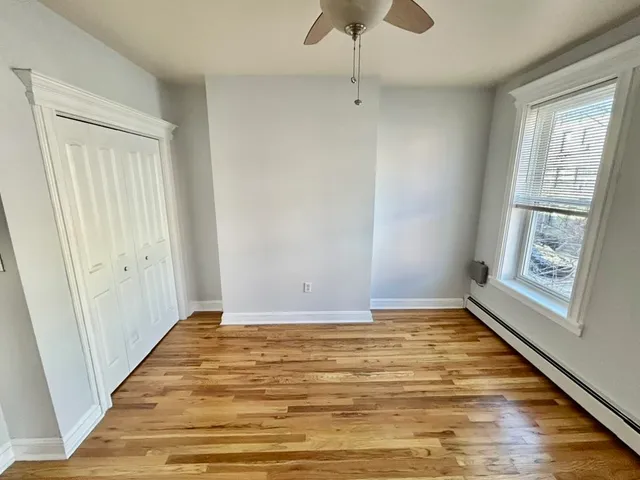 a view of an empty room with window and wooden floor
