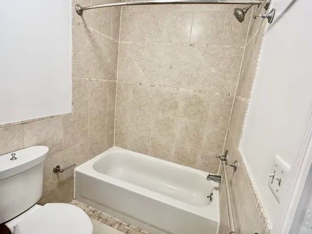 a white toilet sitting next to a bath tub and a shower