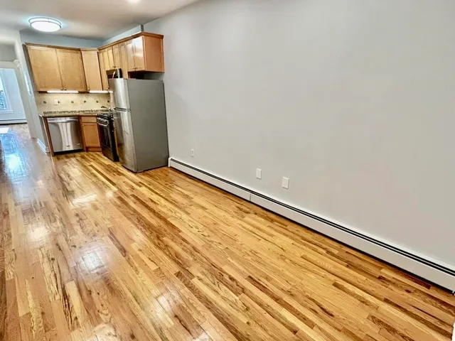 a view of a kitchen with refrigerator and wooden floor