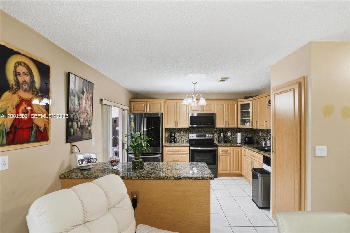 13741 Southwest 160th Terrace Miami, FL 33177 - Photo 11 of 34 a kitchen with stainless steel appliances kitchen island granite countertop a refrigerator and a stove top oven
