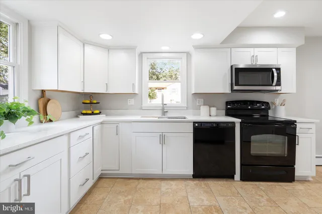 a kitchen with white cabinets appliances and a window