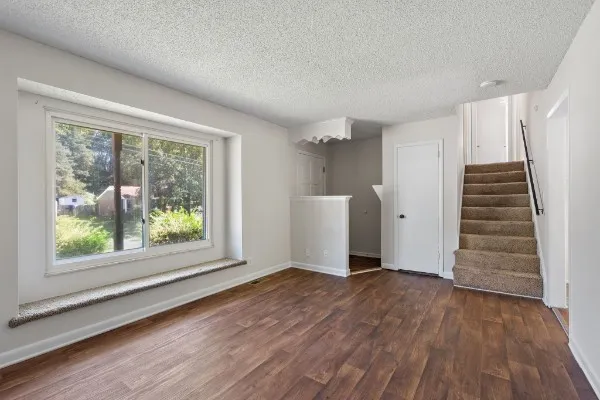 a view of an empty room with wooden floor and a window