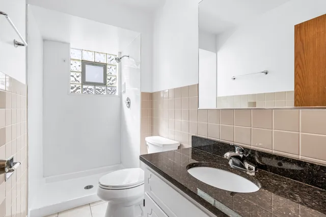 a bathroom with a granite countertop sink toilet a mirror and shower