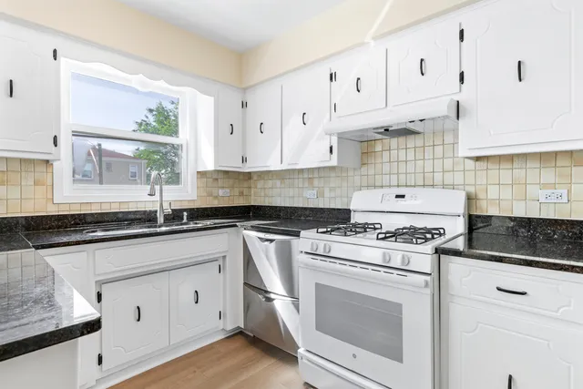 a kitchen with granite countertop white cabinets and white appliances