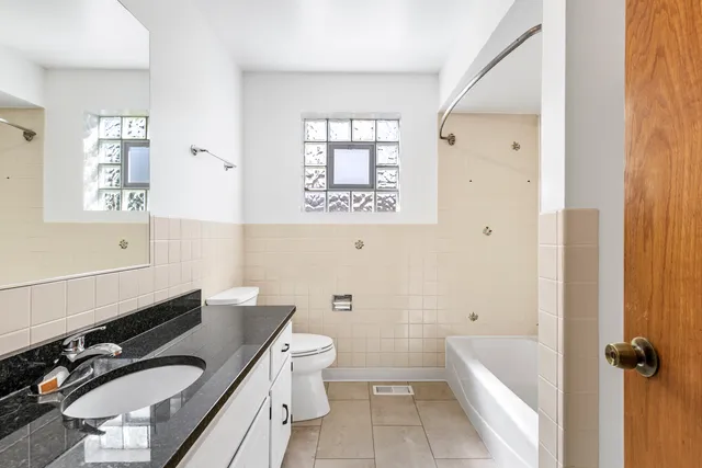 a bathroom with a granite countertop bathtub sink vanity mirror and toilet