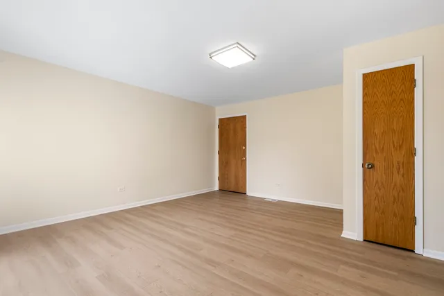 a view of an empty room with wooden floor and closet
