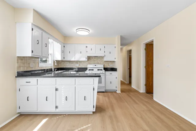 a kitchen with granite countertop white cabinets and refrigerator