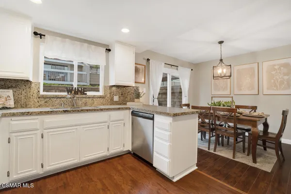a kitchen with granite countertop a stove a sink a dining table and chairs