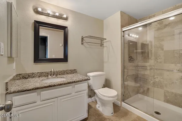 a bathroom with a granite countertop sink a toilet and shower