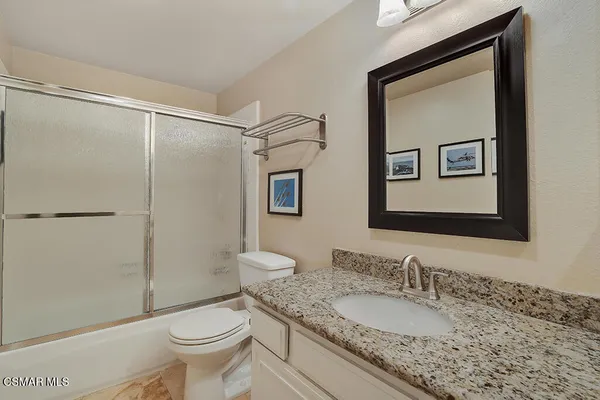 a bathroom with a granite countertop sink toilet and shower