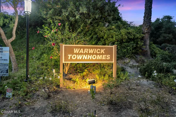 a sign broad in front of the red and white house