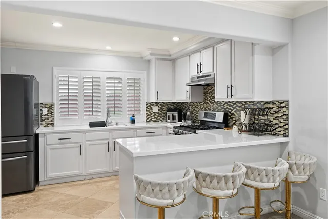a kitchen with stainless steel appliances granite countertop a sink a stove a refrigerator cabinets and a dining table