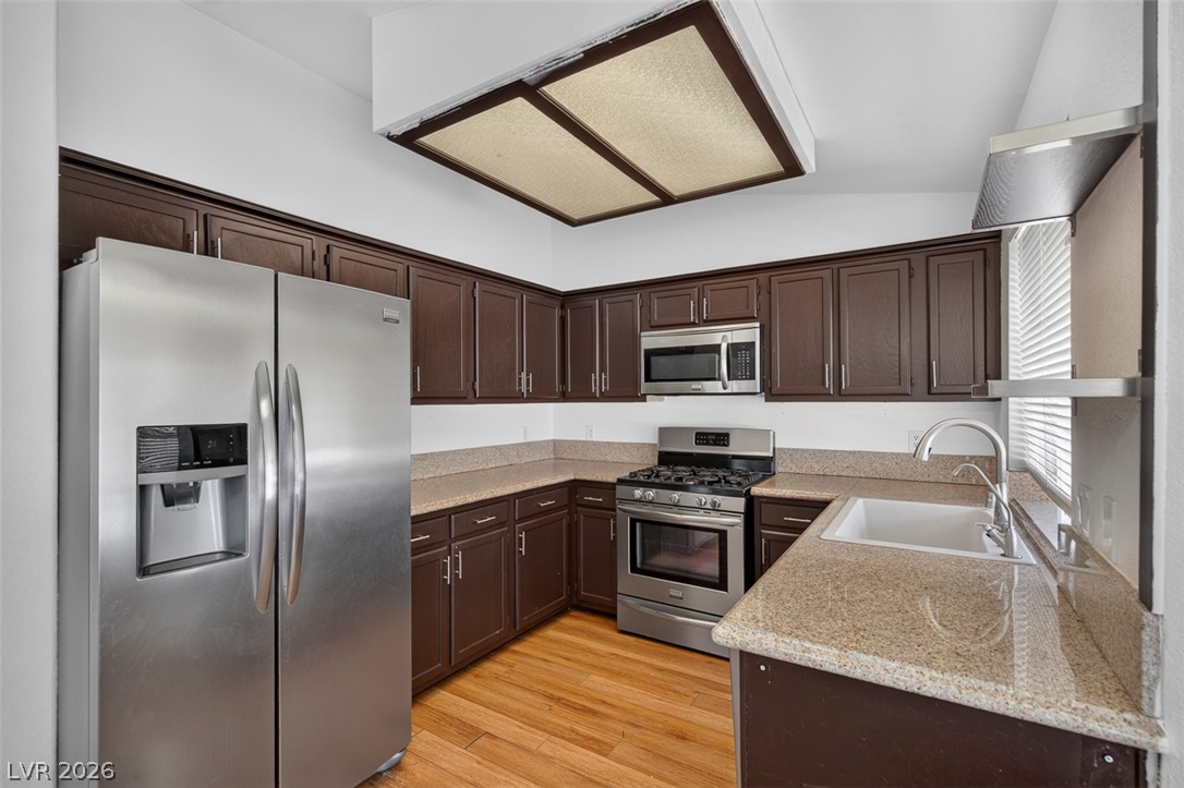 2609 Shakespeare Road Las Vegas, NV 89108 - Photo 16 of 41 A compact culinary space features abundant dark cabinetry, stone counters, and durable wood flooring.