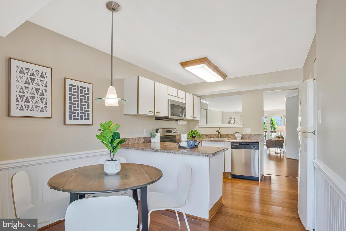 7002 Channel Village Court, Unit 101 Annapolis, MD 21403 - Photo 20 of 48 a kitchen with stainless steel appliances granite countertop a refrigerator a stove a kitchen island with a dining table and chairs