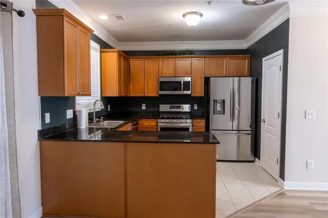 a kitchen with stainless steel appliances granite countertop a refrigerator a stove a sink and a microwave