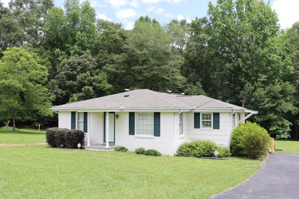 a white house with a small yard and large trees