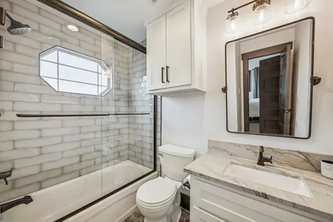 a bathroom with a granite countertop toilet a sink and mirror