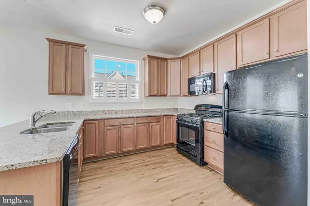 a kitchen with granite countertop a sink stainless steel appliances and cabinets