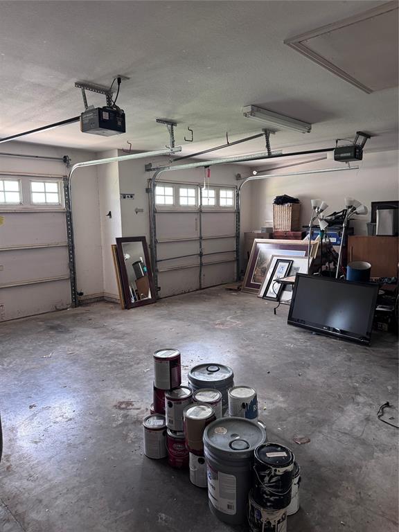 1704 South Bowen Road Pantego, TX 76013 - Photo 31 of 37 Two-car garage featuring concrete flooring, two garage door openers, and fluorescent overhead lighting and extra room for storage