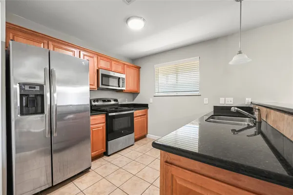 a kitchen with granite countertop stainless steel appliances a refrigerator stove top oven and sink