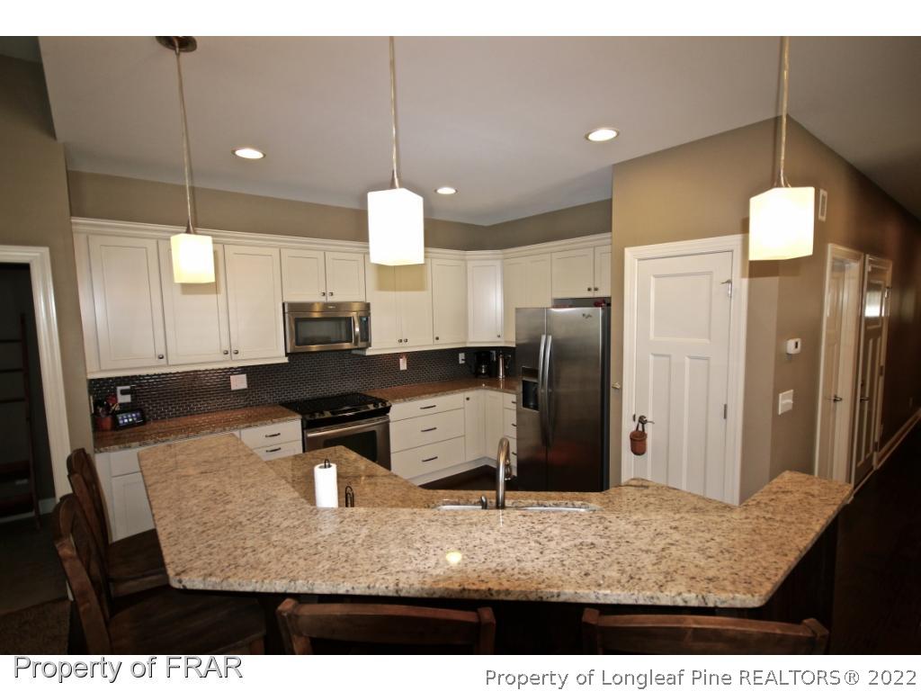 309 Duncan Road Southern Pines, NC 28387 - Photo 9 of 36 a kitchen with stainless steel appliances kitchen island granite countertop a refrigerator a stove and a sink