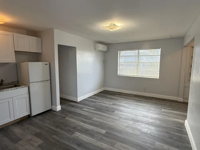 an empty room with wooden floor cabinet and windows
