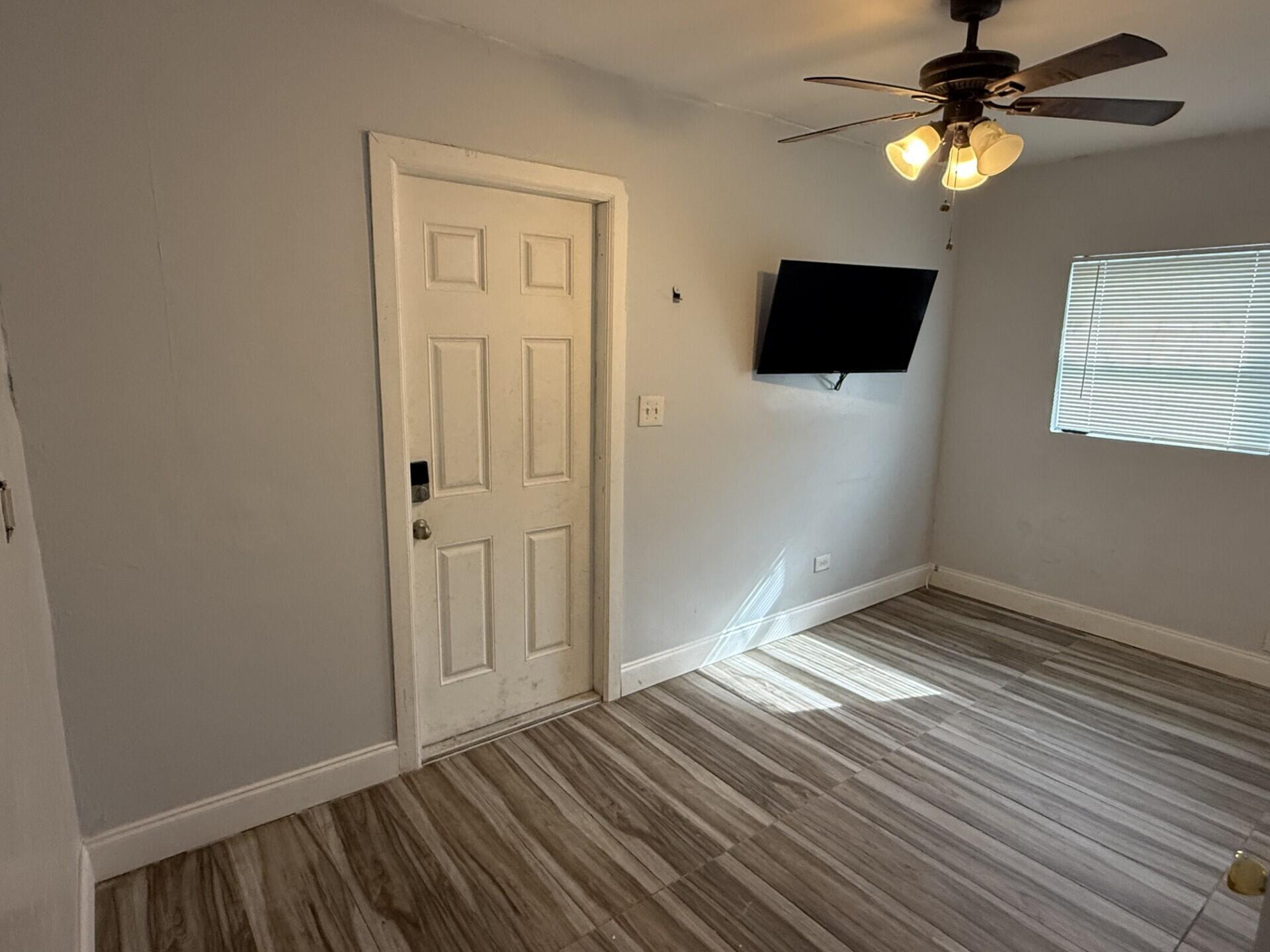 131 East 27th Street, Unit 1 Riviera Beach, FL 33404 - Photo 5 of 10 a view of an empty room with window a ceiling fan and wooden floor