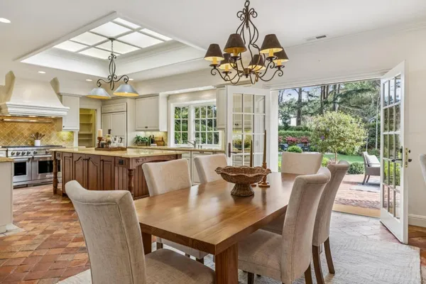 a view of a dining room with furniture a chandelier and large windows