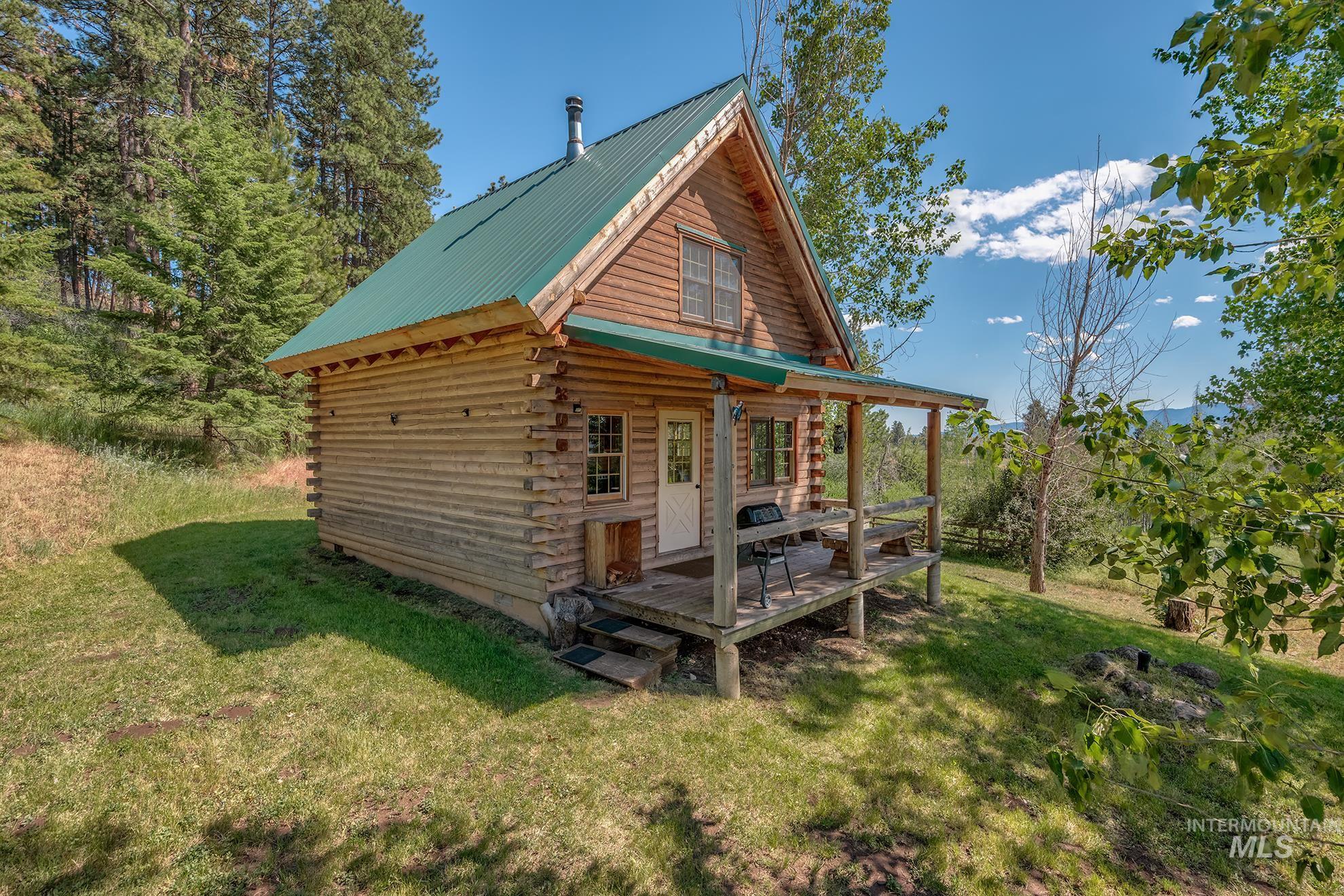 2150 Seid Creek Road Cambridge, ID 83610 - Photo 33 of 50 Log cabin exterior featuring a green metal roof, a covered porch with wood railing, and natural wood siding