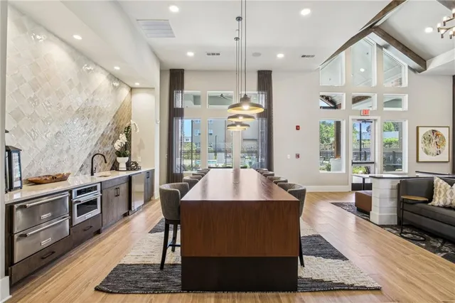 a living room with stainless steel appliances kitchen island granite countertop a stove a sink dishwasher and a dining table with wooden floor