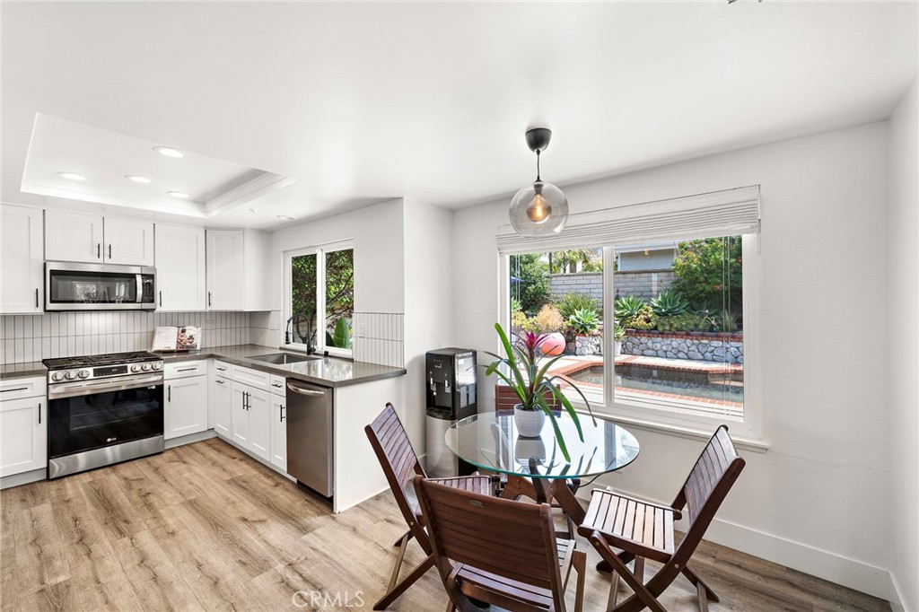 522 Calle Cuadra San Clemente, CA 92673 - Photo 17 of 37 a kitchen with stainless steel appliances granite countertop a stove top oven a sink dishwasher a dining table and chairs with wooden floor