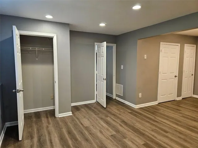 an empty room with wooden floor & closet area