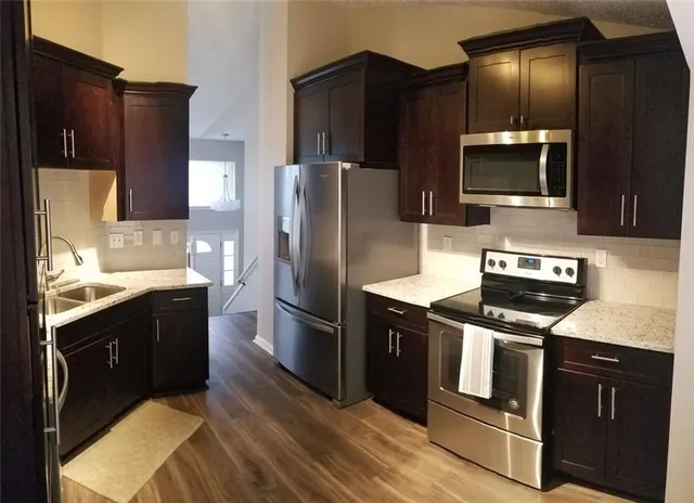 a kitchen with stainless steel appliances wooden cabinets a sink and a refrigerator