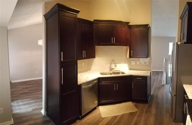 a kitchen with stainless steel appliances granite countertop a refrigerator a sink and wooden cabinets