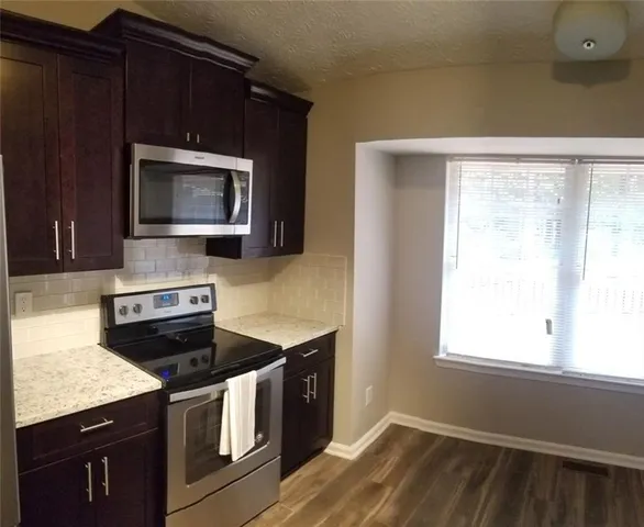 a kitchen with granite countertop cabinets stainless steel appliances and a window