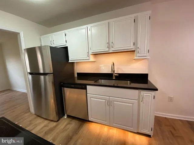 a kitchen with granite countertop a refrigerator sink and cabinets
