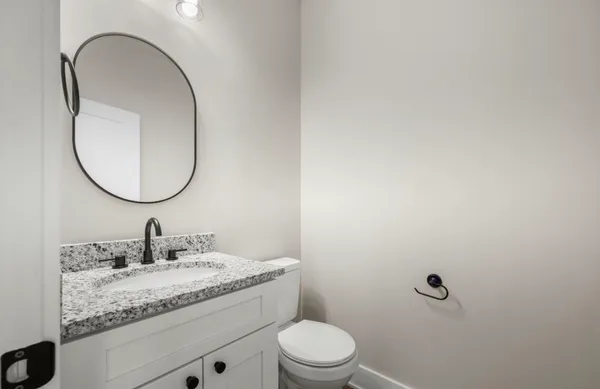 a bathroom with a granite countertop sink a toilet and a mirror